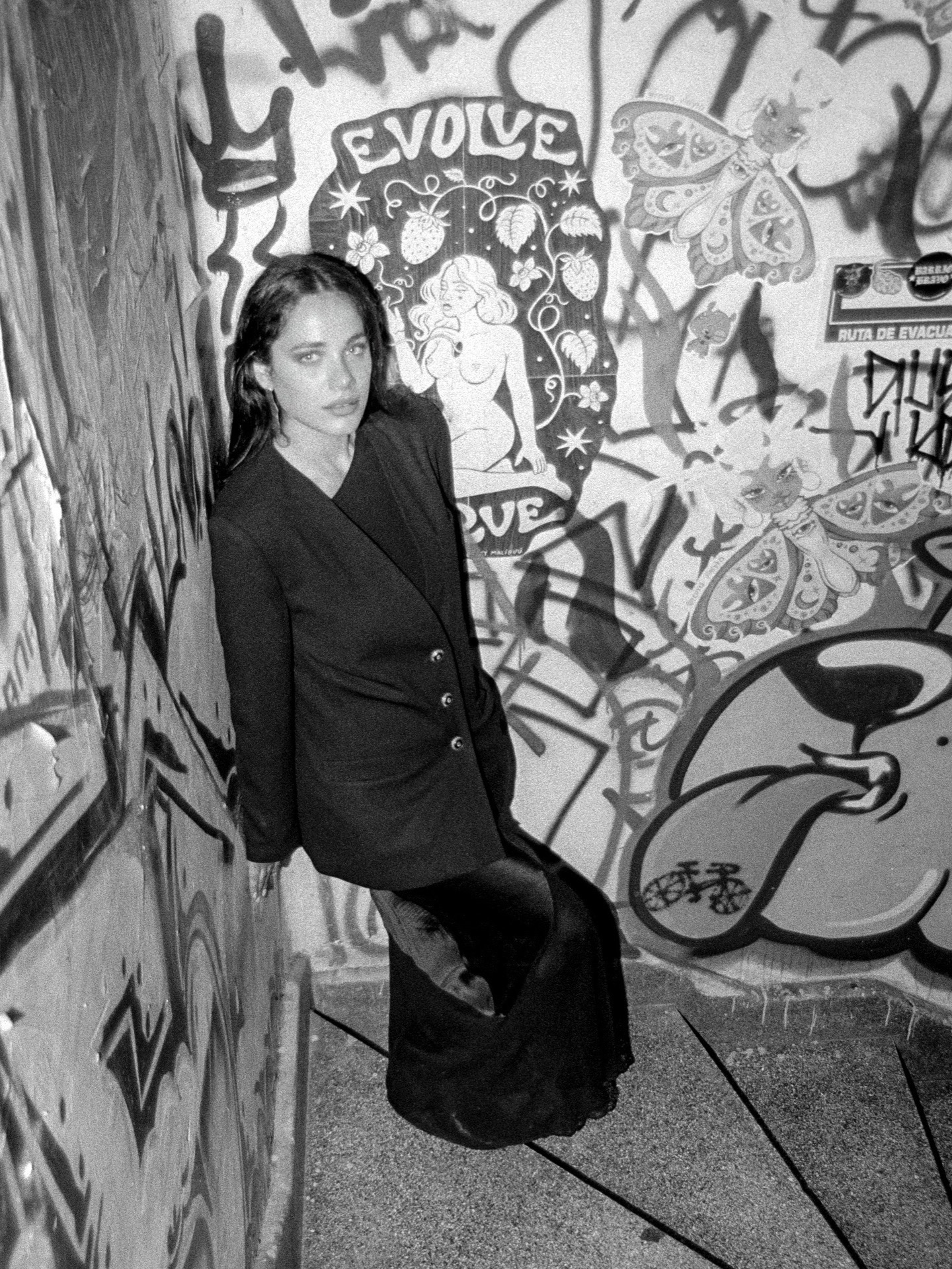 Portrait beside a graffiti-covered wall in black and white