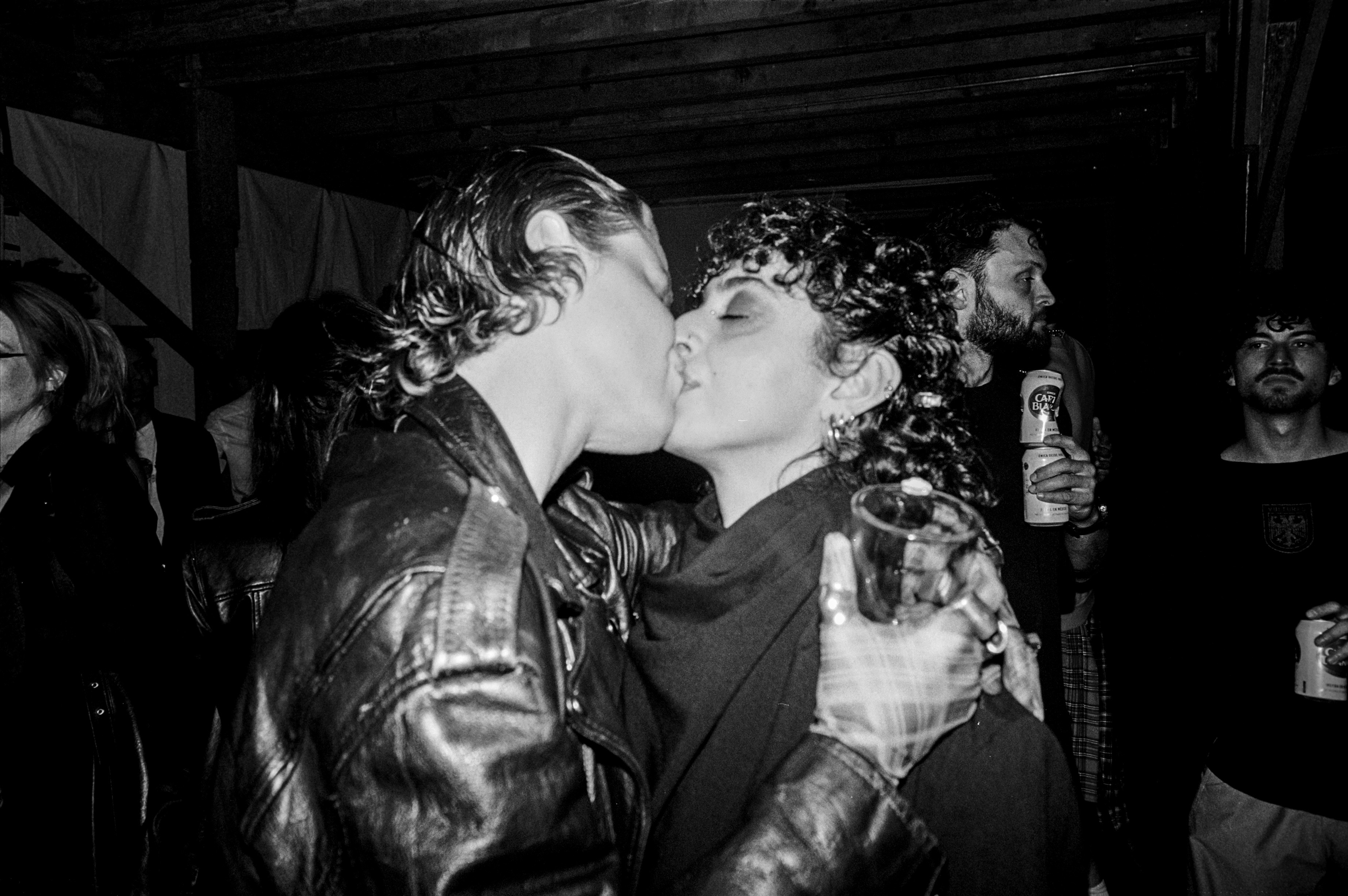 Two people kissing at a nighttime party in black and white