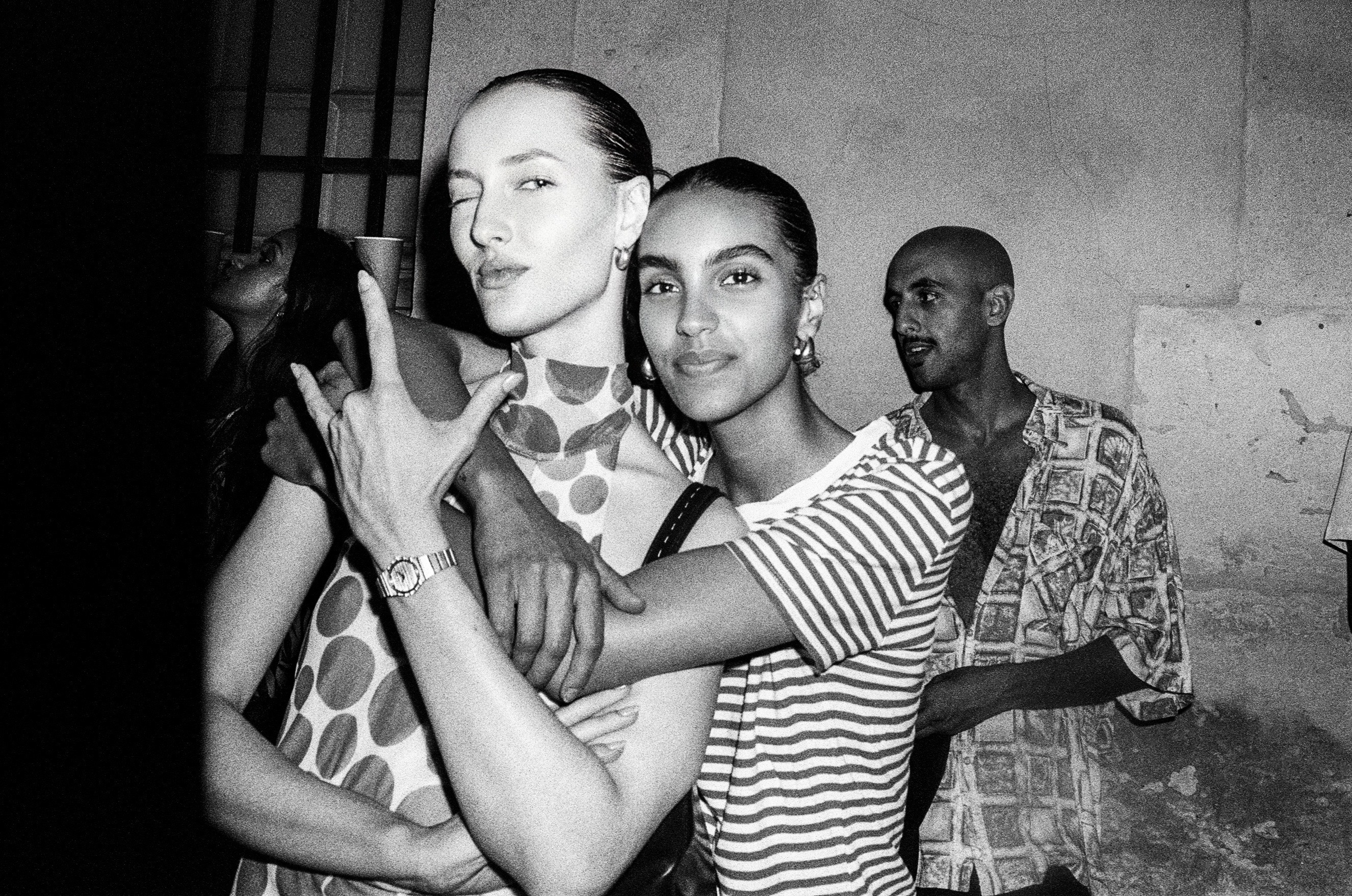 Two friends embracing at a party in black and white