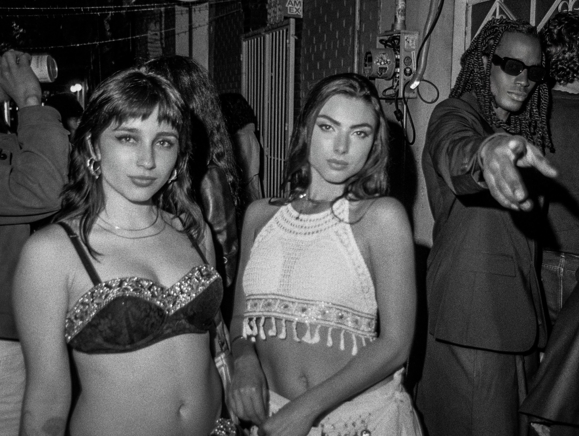 Three friends posing at a nighttime party in black and white