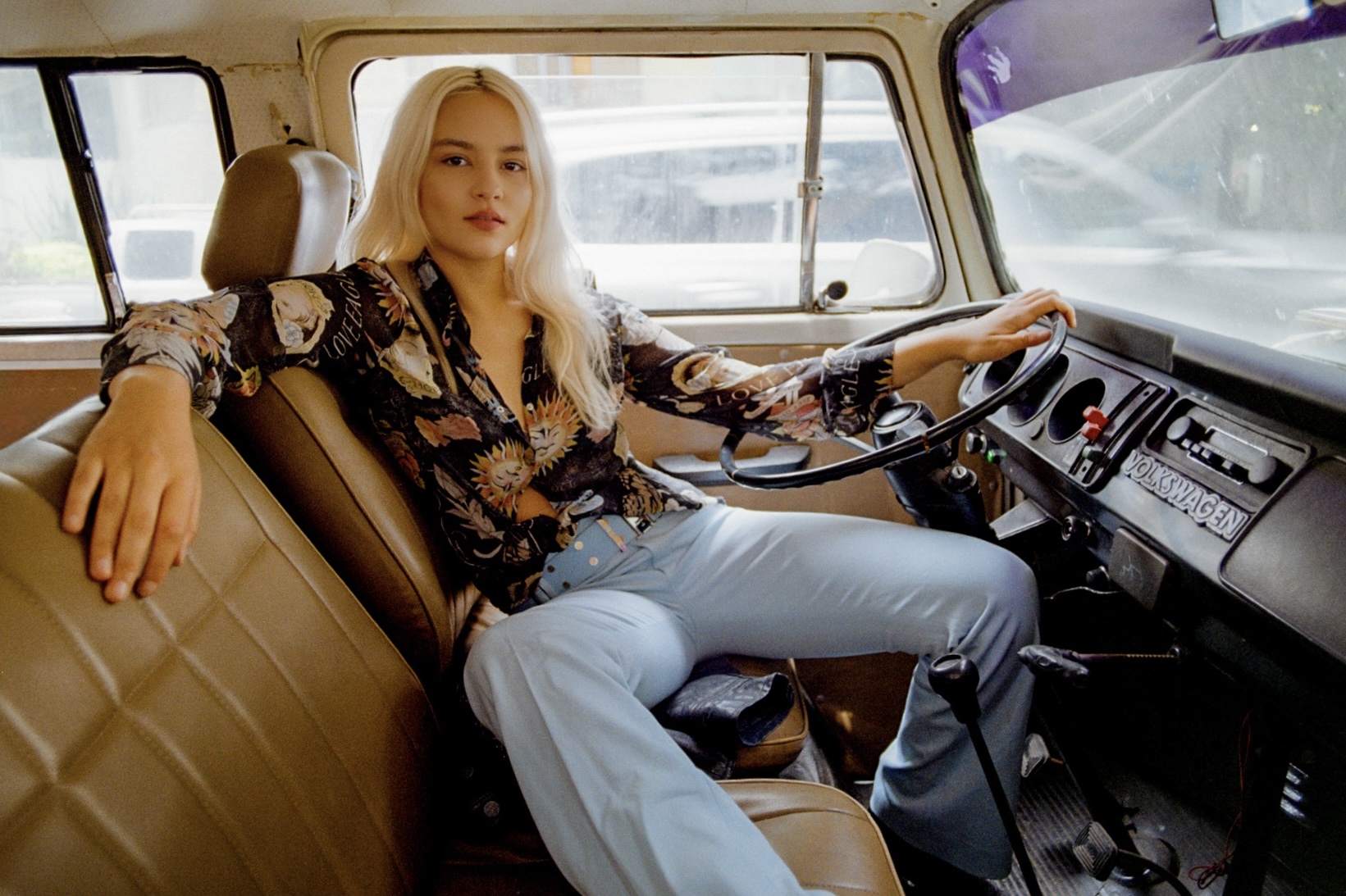 Blonde woman seated behind the wheel of a vintage Volkswagen van