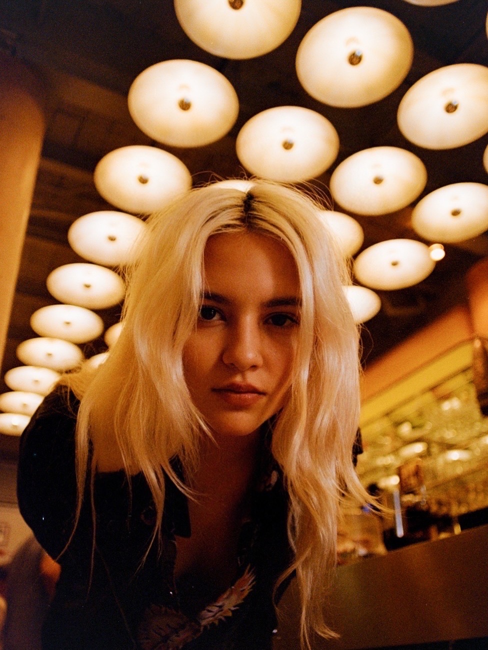 Close portrait beneath a ceiling of glowing lights